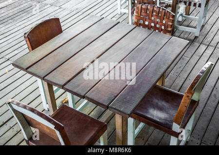 empty wooden table in restaurant with four empty chairs - vintage furniture - Stock Photo