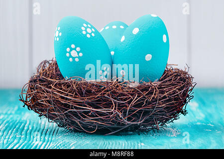 Blue Easter eggs in nest on blue wooden background. Stock Photo
