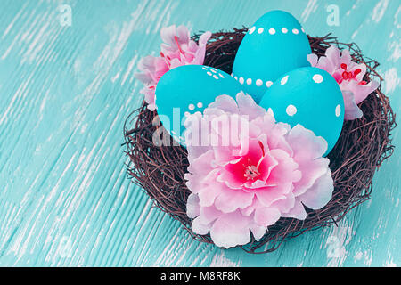Blue Easter eggs in nest on blue wooden background. Stock Photo