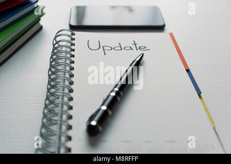 Update - handwritten text in a notebook on a desk. Project update checklist. Notebook, pen and books Stock Photo