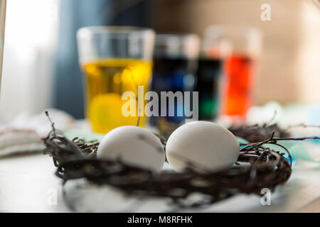 Easter, holidays, tradition and people concept - coloring Easter eggs in glass cups with dyes. Happy Easter concept Stock Photo