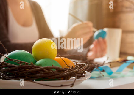 Easter, holidays, tradition and people concept - close up of woman hands coloring easter eggs with colors and brush. Happy Easter concept Stock Photo