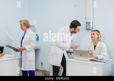 Group of doctors working together on a laptop in a modern office Stock Photo