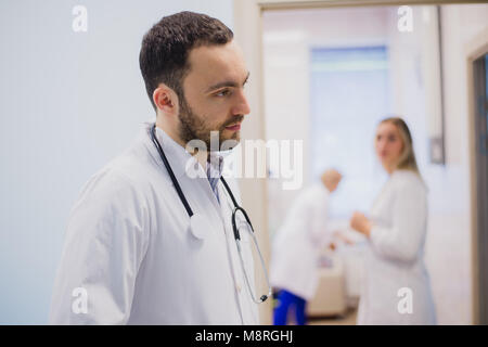 Side view of thoughtful young doctor in medical uniform listening to patient Stock Photo
