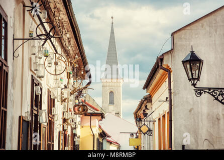 Hrnciarska street with Calvinist church in Kosice, Slovak republic. Folk art theme. Religious architecture. Yellow photo filter. Stock Photo