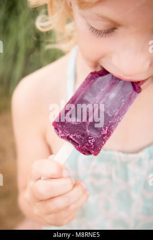 High angle view of girl eating popsicle while standing outdoors Stock Photo