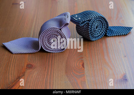 two men's ties, rolled up on a wooden background Stock Photo