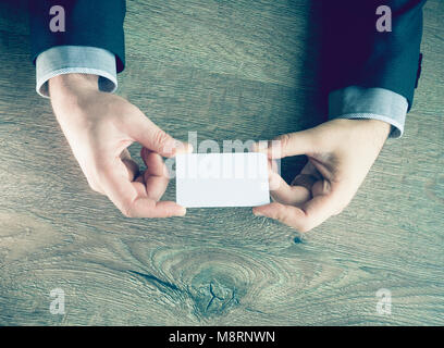 Man's hand showing business card - closeup shot on dark wooden background Stock Photo