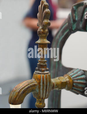 Public metal yellow faucet fountain with drinking  water flowing in old traditional city Stock Photo