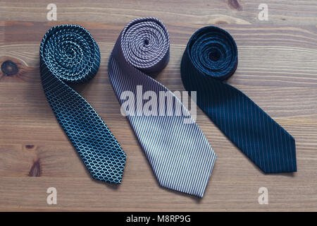 three men's tie rolled into a roll on a wooden background Stock Photo