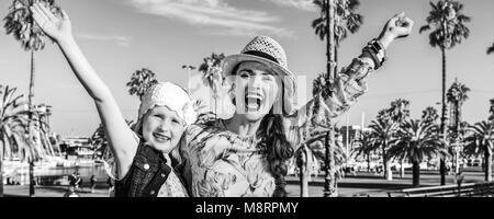 Summertime at colorful Barcelona. smiling elegant mother and daughter travellers on embankment in Barcelona, Spain rejoicing Stock Photo