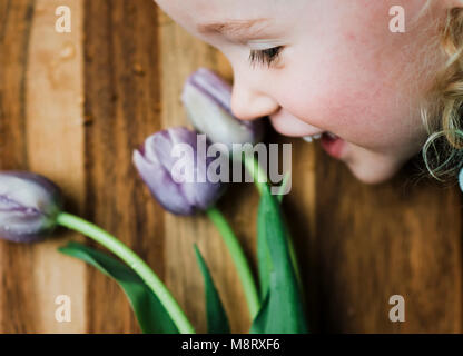 High angle view of smiling girl by purple tulips on table Stock Photo