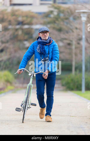 Full length of man with bicycle walking on footpath at park Stock Photo