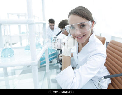 Investigator checking test tubes, Woman wears protective goggles Stock Photo