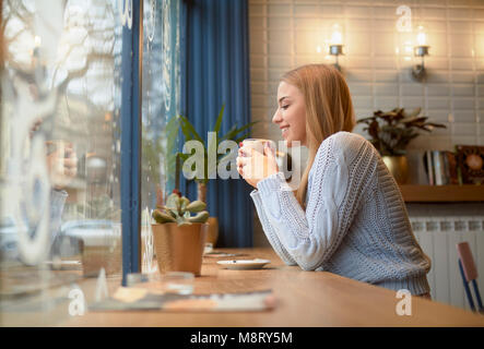 Side view of woman having drink at table in cafe Stock Photo