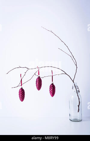 Christmas decorations hanging on twig in bottle against white background Stock Photo