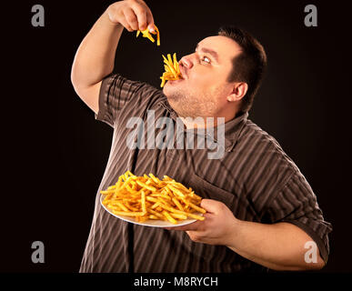 Fat man eating fast food french fries for overweight person. Stock Photo
