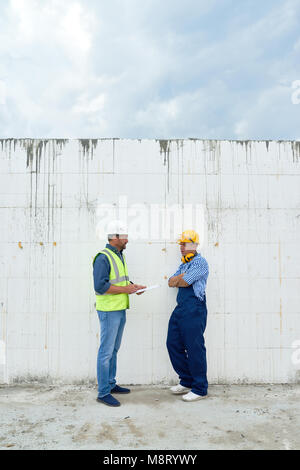 Two Construction Workers Discussing Building Stock Photo
