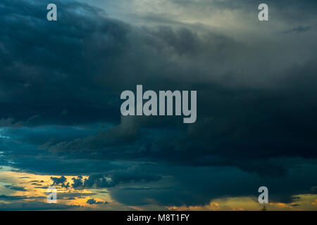 Overcast weather with stratus, cumulus and cumulonimbus clouds during the rain with clear sky and sunset in the background Stock Photo