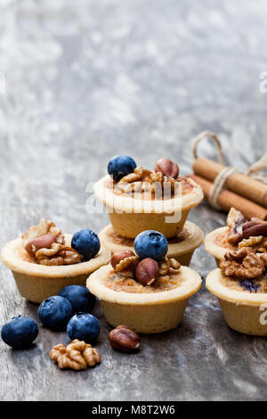 mini  ginger and walnut tarts with blueberry on wooden background Stock Photo
