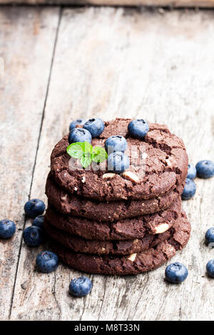 stack  of dark chocolate cookies with fresh blueberry isolated on wooden table Stock Photo