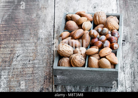 Various  nuts in wooden box on rustic table Stock Photo