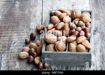 Various  nuts in wooden box on rustic table Stock Photo
