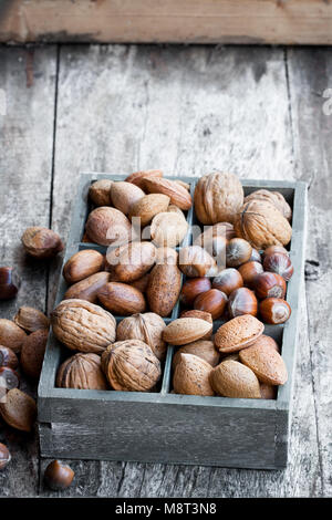 Various  nuts in wooden box on rustic table Stock Photo