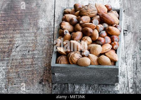 Various  nuts in wooden box on rustic table Stock Photo