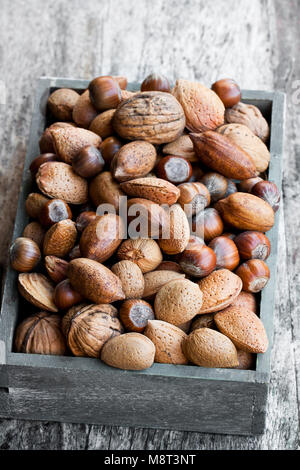 Various  nuts in wooden box on rustic table Stock Photo