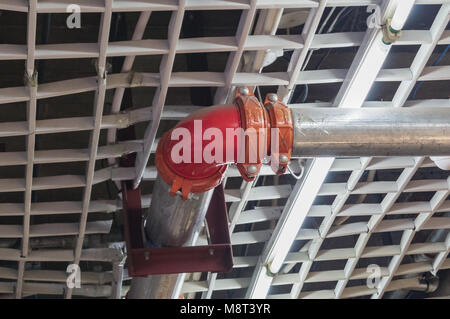 Fire extinguishing system in a public building under the ceiling. Red angled connection of the flange and fitting of the water pipe for fire extinguis Stock Photo