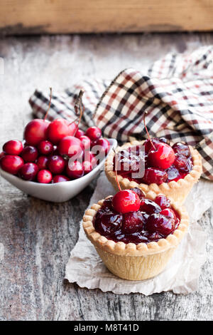 egg  custard tarts with cranberry jam and wild apples on wooden table Stock Photo