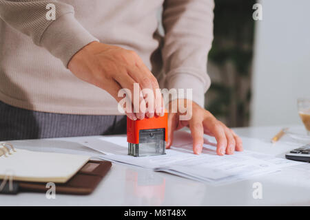 Close-up of male hand stamping document on wooden desk Stock Photo