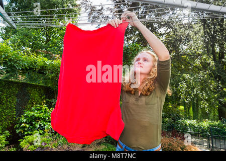 Caucasian girl hangs clothes at washing line outdoors Stock Photo