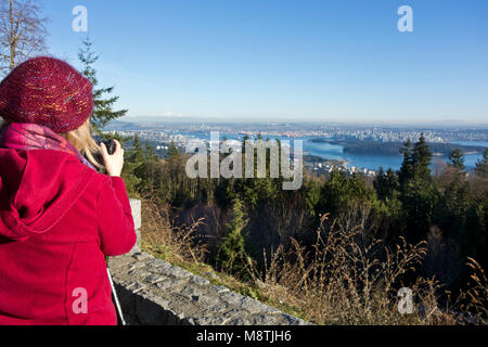 Woman taking a photo of the aerial view of Vancouver, as seen from the Cypress Mountain lookout in West Vancouver. Stock Photo