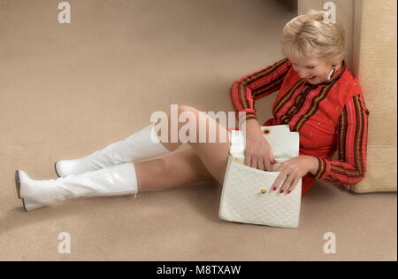 Woman dressed in 1960s style dress with plastic boots and handbag Stock Photo