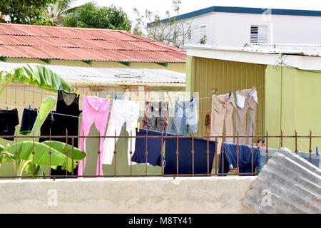 Washed clothes hanging on the wash line attached with colourful pegs. Stock Photo