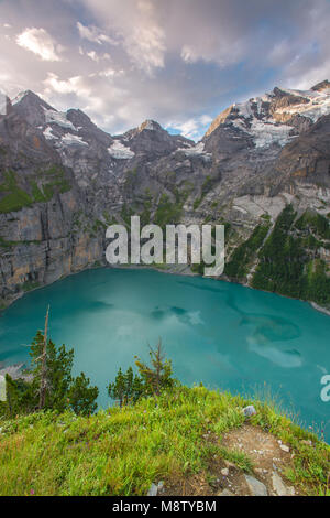 Spectacular view from a high ledge, cliff of an alpine lake at sunrise. Colorful sky, forest and mountains frame a deep blue lake. Switzerland hiking. Stock Photo