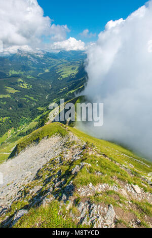 Hardergrat trail, sheer ridge, ridgecrest hiking, sharp edge, dropping to valley and lake below. Enveloping clouds. Swiss Alps summer hiking. Stock Photo