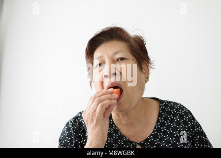Asian senior woman eating ripe papaya sliced at home, lifestyle concept. Stock Photo
