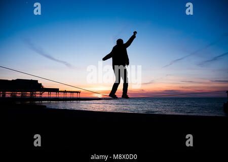 Aberystwyth Wales UK, Tuesday   20 March 2018  UK Weather:   A young man is silhouetted as he practices his ’slack-line’ walking  as the sun sets  gloriously  over Cardigan Bay on cold but clear Spring Equinox evening in Aberystwyth on the west coast of Wales.   With day and night of equal length, the spring equinox today marks the start of ’astronomical spring’     photo © Keith Morris  / Alamy Live News Stock Photo