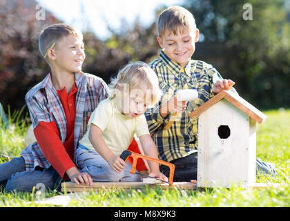 Kids brothers making nesting box together on lawns in summertime Stock Photo