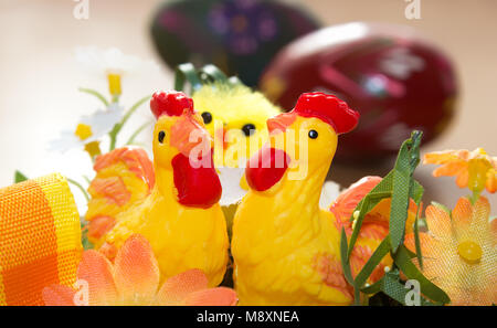 Easter decorations. In the foreground there are two hens behind them is a chicken and in the background is a painted egg. Stock Photo