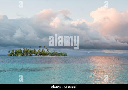 Island with palm trees, scenic sky and clear water - Stock Photo