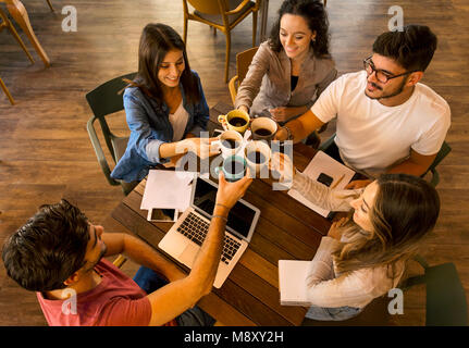 Group of friends studying together and making a toast with coffee Stock Photo