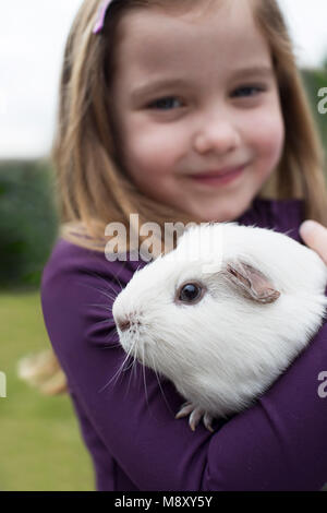 Portrait Of Girl In Garden Looking After Pet Guinea Pig Stock Photo