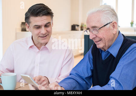 Male Neighbor Showing Senior Man How To Use Mobile Phone Stock Photo