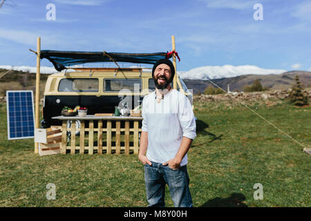 Midle aged beared man in front of a Volkswagen food truck in the nature Stock Photo