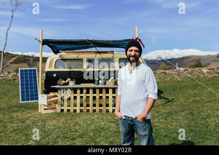 Midle aged beared man in front of a Volkswagen food truck in the nature Stock Photo