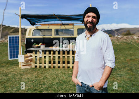 Midle aged beared man in front of a Volkswagen food truck in the nature Stock Photo